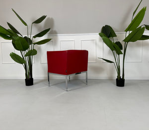 Gebrauchter roter Brühl Randolph Designer Leder Sessel vor einer Wand, stilvoll und modern eingerichtet.