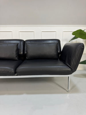 Gebrauchtes schwarzes Brühl Roro Designer Leder Ausstellungsstück Sofa vor einer Wand, stilvoll und modern eingerichtet.