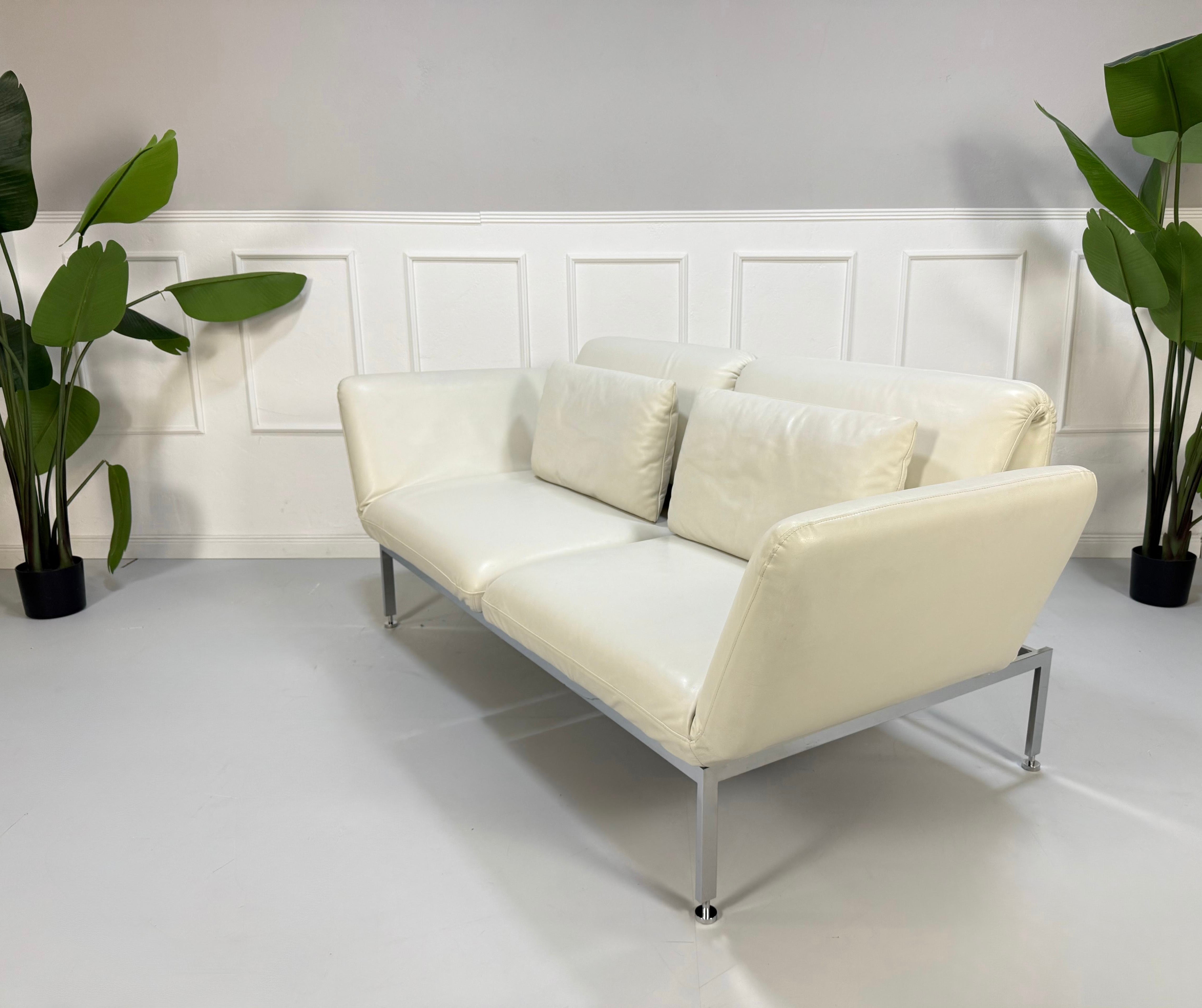 Gebrauchtes weißes Brühl Roro Designer Leder Sofa vor einer Wand, stilvoll und modern eingerichtet.
