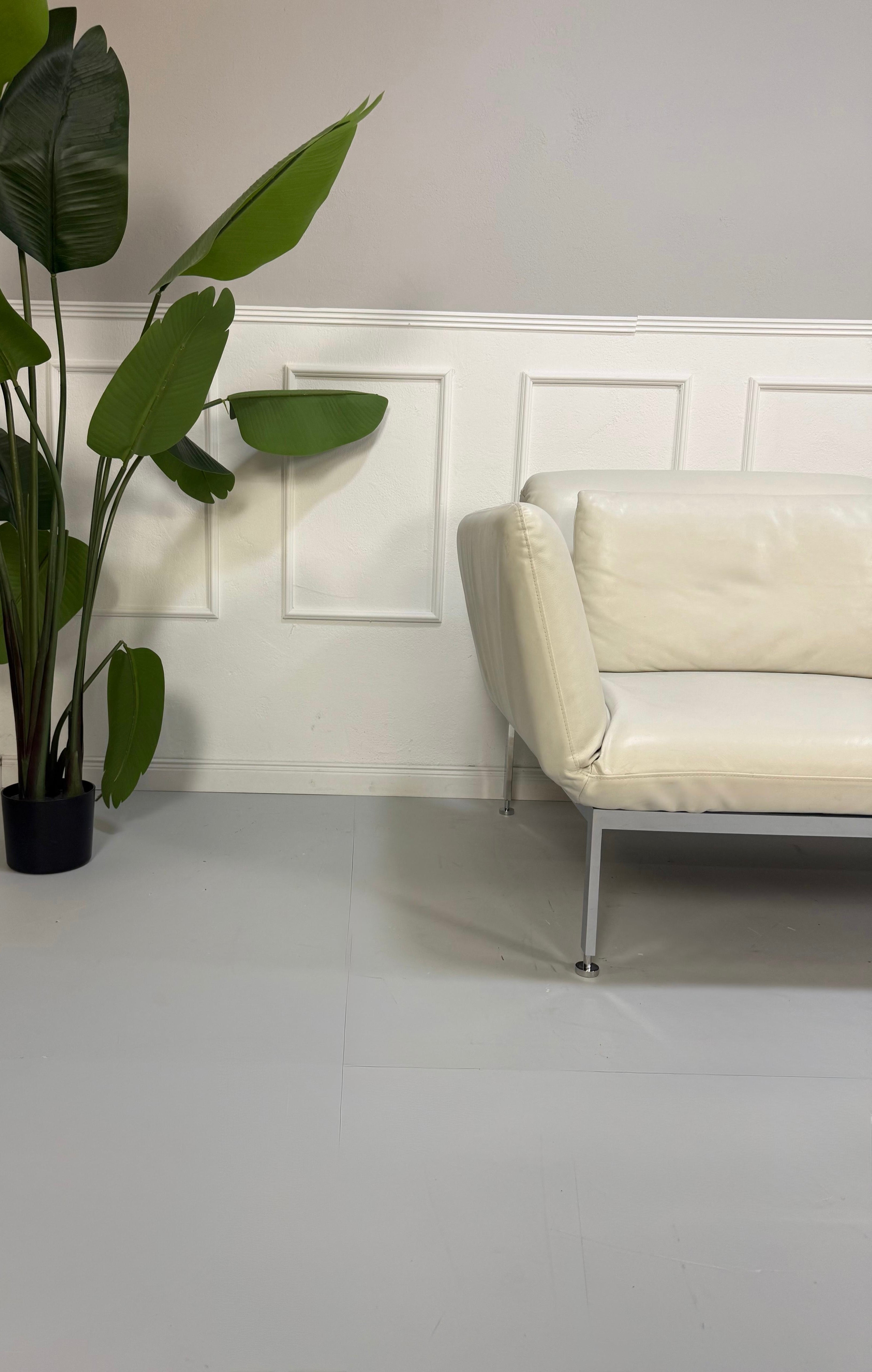 Gebrauchtes weißes Brühl Roro Designer Leder Sofa vor einer Wand, stilvoll und modern eingerichtet.