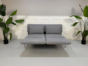 Erneuertes Brühl Roro Designer Stoff Sofa in der Farbe Grau vor einer Wand, stilvoll und modern eingerichtet.