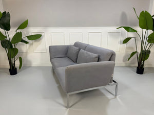 Erneuertes Brühl Roro Designer Stoff Sofa in der Farbe Grau vor einer Wand, stilvoll und modern eingerichtet.