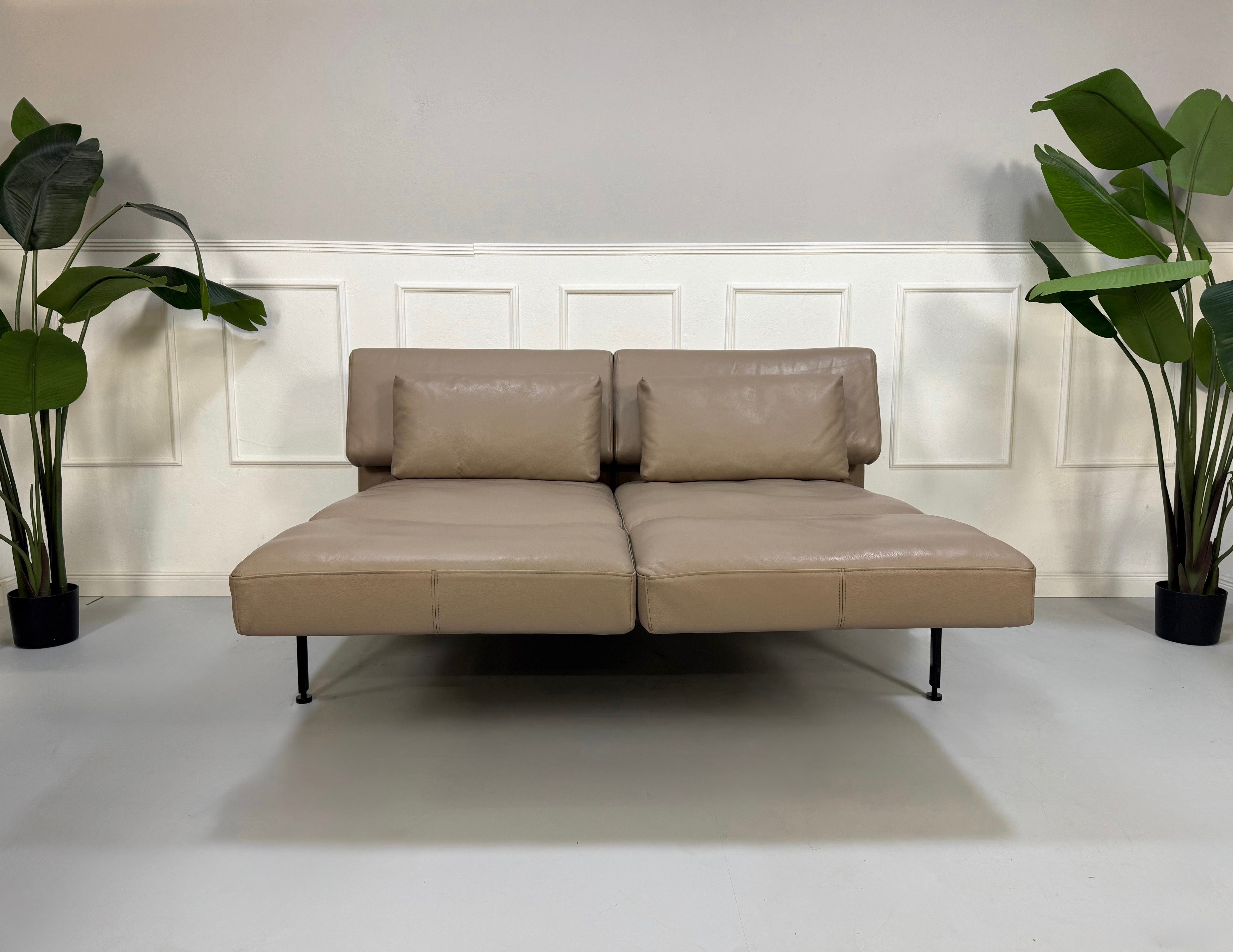 Erneuertes graues Brühl Roro Soft Designer Stoff Sofa vor einer Wand, stilvoll und modern eingerichtet.