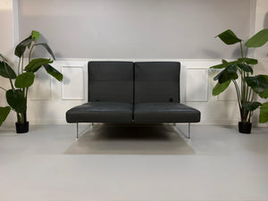 Erneuertes graues Brühl Roro Soft Designer Leder Sofa vor einer Wand, stilvoll und modern eingerichtet.