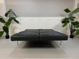 Erneuertes graues Brühl Roro Soft Designer Leder Sofa vor einer Wand, stilvoll und modern eingerichtet.