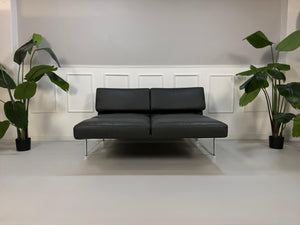 Erneuertes graues Brühl Roro Soft Designer Leder Sofa vor einer Wand, stilvoll und modern eingerichtet.