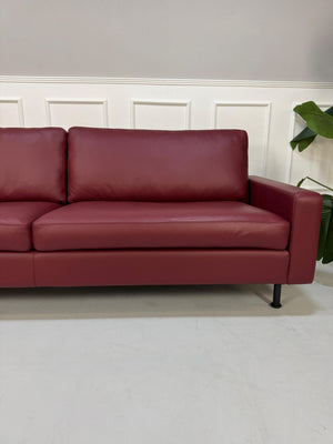 Gebrauchtes rotes COR Conseta Designer Leder Sofa vor einer Wand, stilvoll und modern eingerichtet.