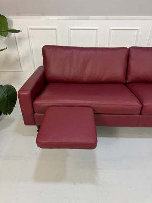 Gebrauchtes rotes COR Conseta Designer Leder Sofa vor einer Wand, stilvoll und modern eingerichtet.