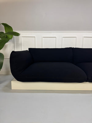 Refurbished COR Jalis in der Farbe Schwarz Designer Stoff Sofa vor einer Wand, stilvoll und modern eingerichtet.