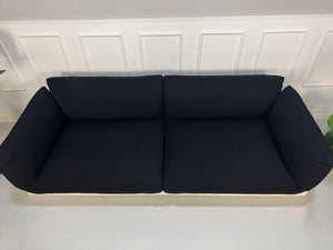 Refurbished COR Jalis in der Farbe Schwarz Designer Stoff Sofa vor einer Wand, stilvoll und modern eingerichtet.