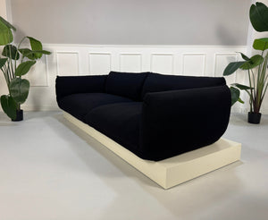 Refurbished COR Jalis in der Farbe Schwarz Designer Stoff Sofa vor einer Wand, stilvoll und modern eingerichtet.