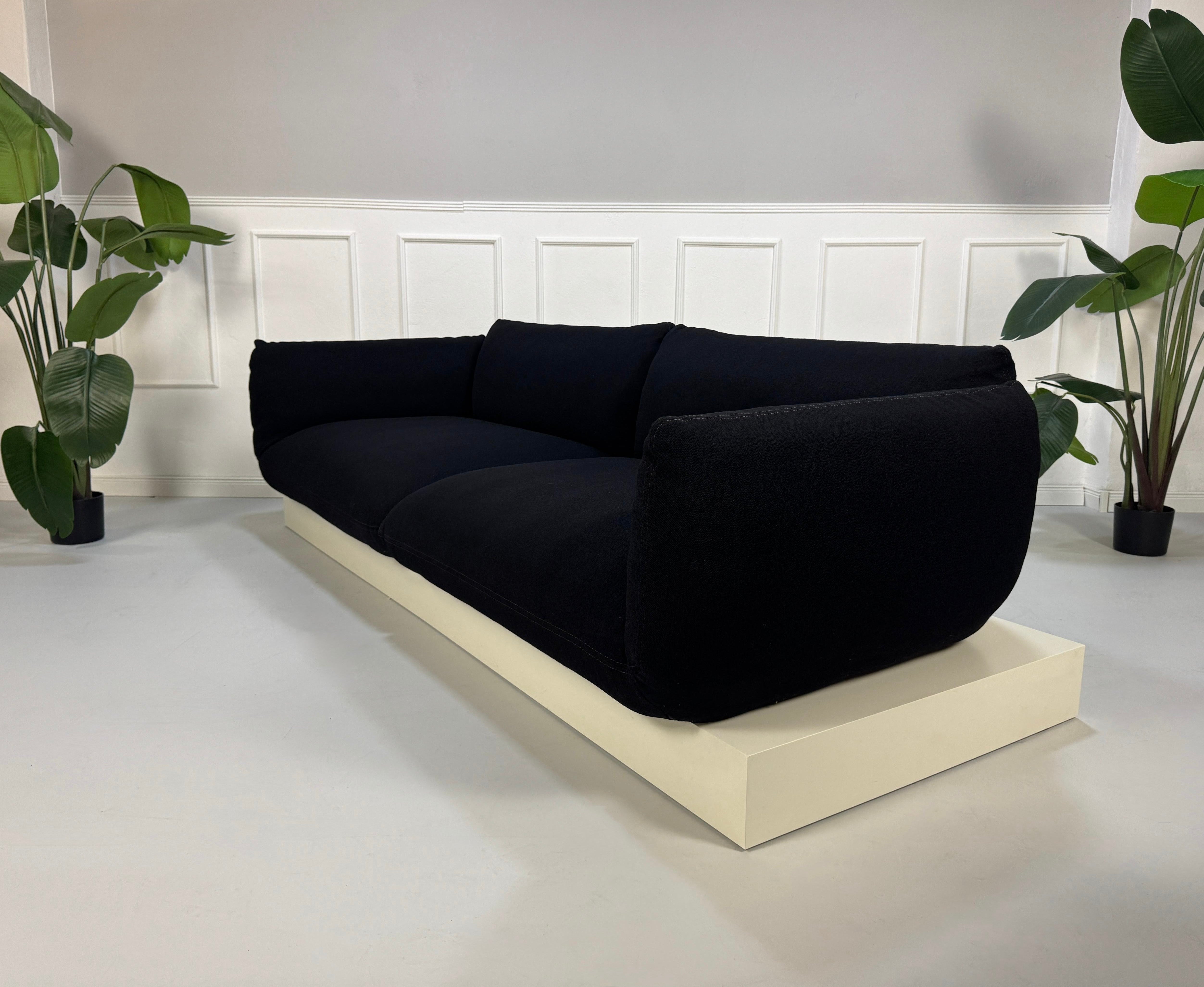 Refurbished COR Jalis in der Farbe Schwarz Designer Stoff Sofa vor einer Wand, stilvoll und modern eingerichtet.