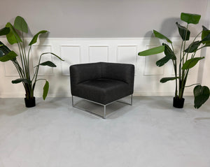 Gebrauchtes graues COR Mell Designer Stoff Sofa vor einer Wand, stilvoll und modern eingerichtet.