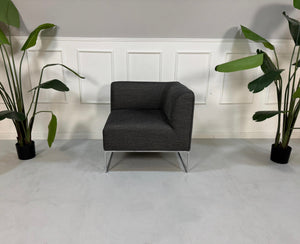 Gebrauchtes graues COR Mell Designer Stoff Sofa vor einer Wand, stilvoll und modern eingerichtet.