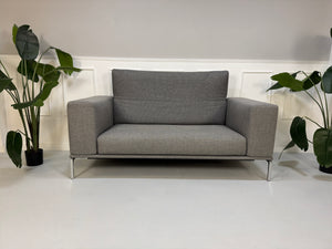 Gebrauchtes graues Cassina Moov Zweisitzer Designer Stoff Sofa vor einer Wand, stilvoll und modern eingerichtet.