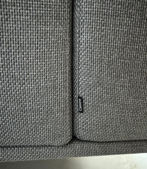 Gebrauchtes graues Cassina Moov Zweisitzer Designer Stoff Sofa vor einer Wand, stilvoll und modern eingerichtet.