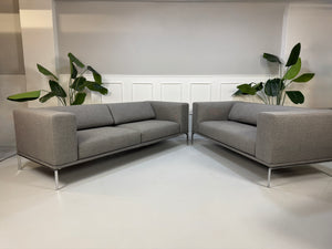 Gebrauchtes graues Cassina Moov Zweisitzer Designer Stoff Sofa vor einer Wand, stilvoll und modern eingerichtet.