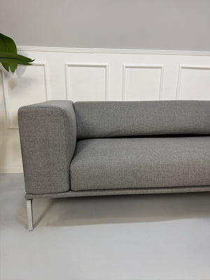 Gebrauchtes graues Cassina Moov Zweisitzer Designer Stoff Sofa vor einer Wand, stilvoll und modern eingerichtet.
