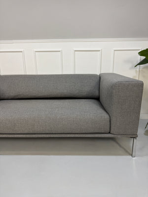 Gebrauchtes graues Cassina Moov Zweisitzer Designer Stoff Sofa vor einer Wand, stilvoll und modern eingerichtet.