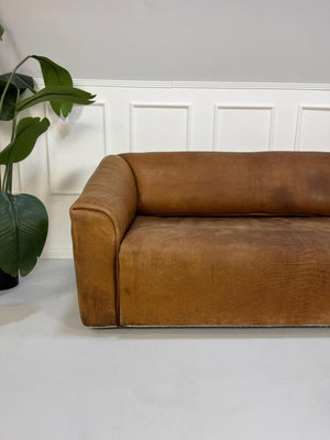 Gebrauchtes braunes DeSede DS47 Designer Leder Sofa vor einer Wand, stilvoll und modern eingerichtet.
