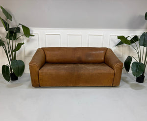 Gebrauchtes braunes DeSede DS47 Designer Leder Sofa vor einer Wand, stilvoll und modern eingerichtet.