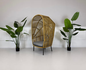 Gebrauchter outdoor DEDON Rilly Cocoon Garten Stuhl vor einer Wand, stilvoll und modern eingerichtet.