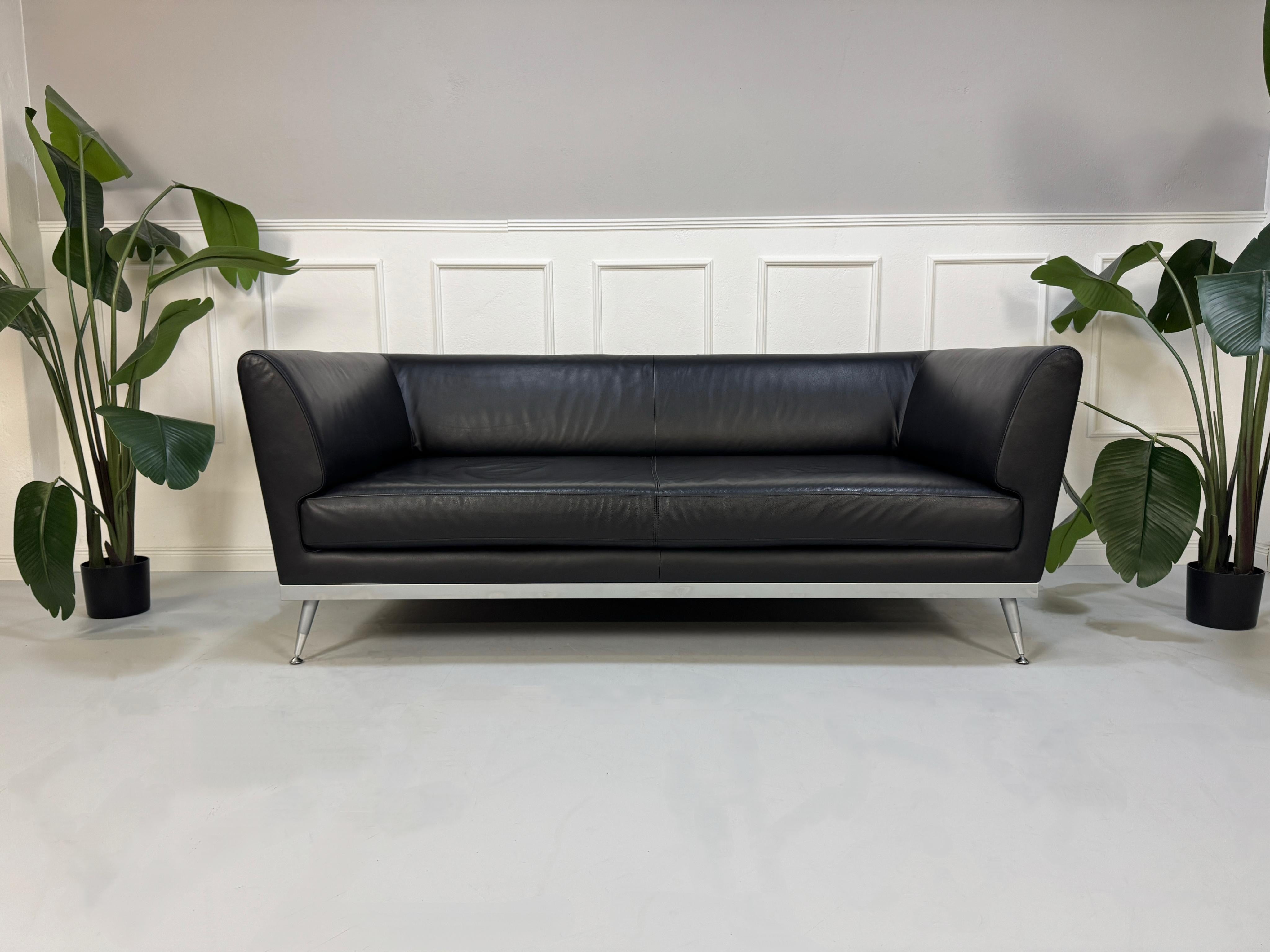 Gebrauchtes schwarzes Ligne Roset Fugue Designer Leder Sofa vor einer Wand, stilvoll und modern eingerichtet.