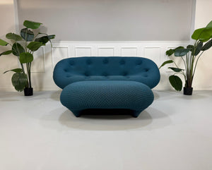 Gebrauchtes blaues Ligne Roset Ploum Designer Stoff Sofa mit Hocker vor einer Wand, stilvoll und modern eingerichtet.