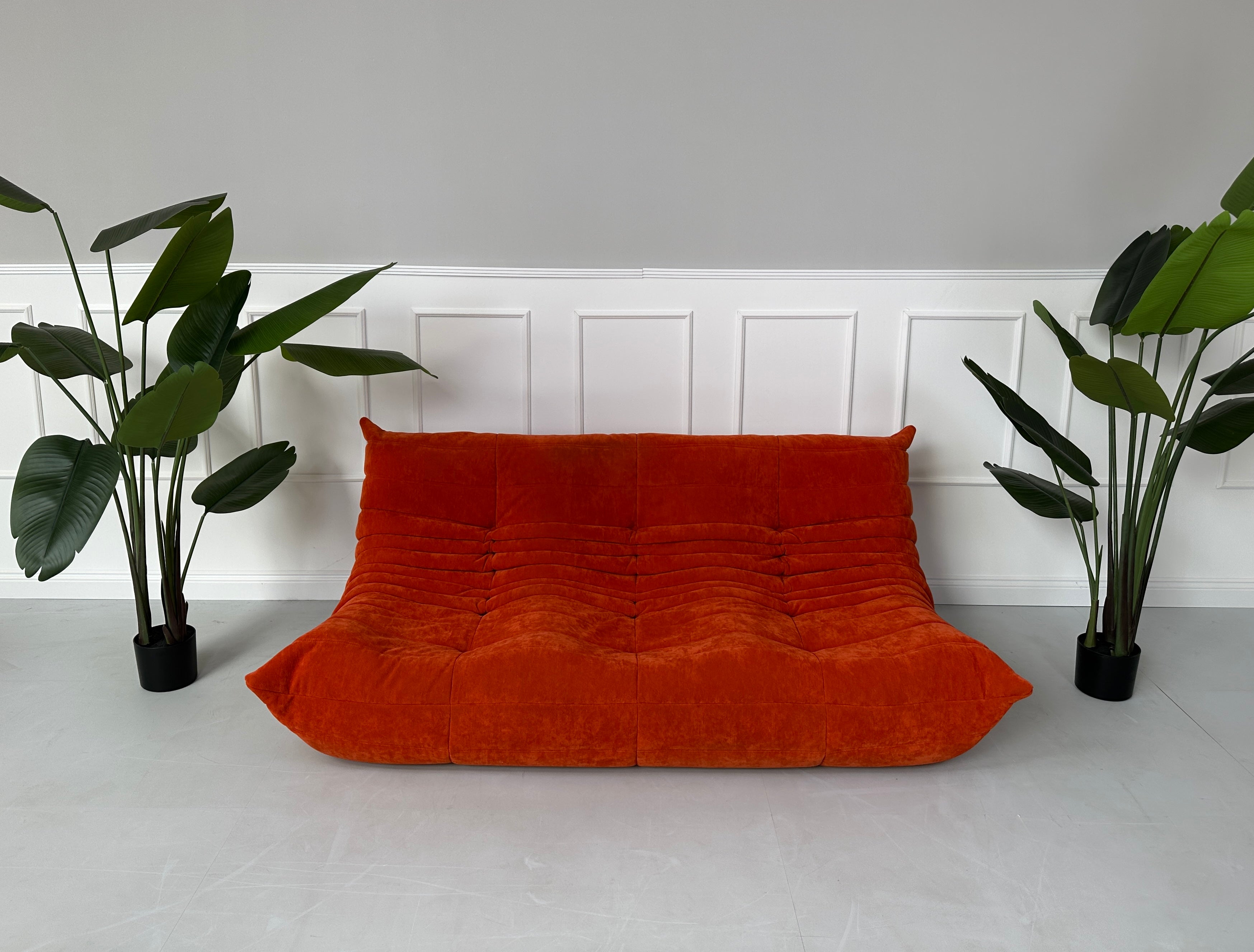 Gebrauchtes oranges Ligne Roset TOGO Designer Stoff Sofa vor einer Wand, stilvoll und modern eingerichtet.