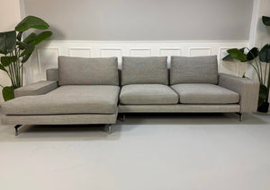 Refurbished graues Minotti Sherman Designer Stoff Sofa vor einer Wand, stilvoll und modern eingerichtet.