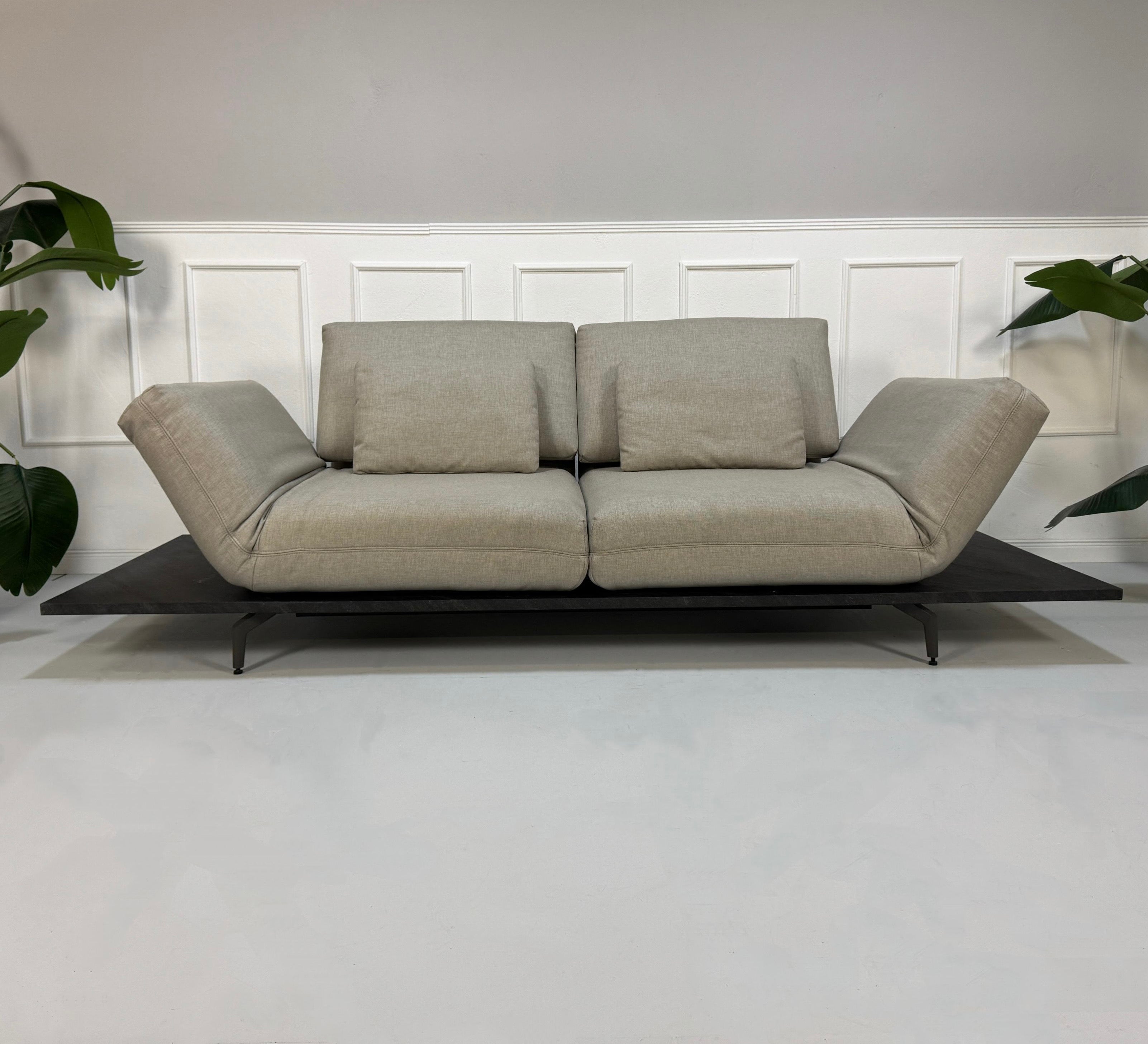 Gebrauchtes beiges Rolf Benz Aura Designer Stoff Sofa vor einer Wand, stilvoll und modern eingerichtet.