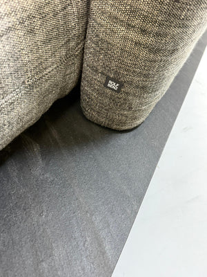 Gebrauchtes graues Rolf Benz Aura Designer Stoff Sofa vor einer Wand, stilvoll und modern eingerichtet.