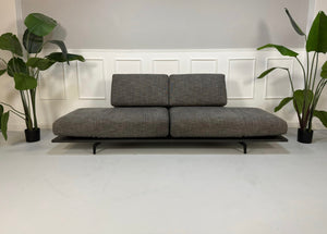 Gebrauchtes graues Rolf Benz Aura Designer Stoff Sofa vor einer Wand, stilvoll und modern eingerichtet.