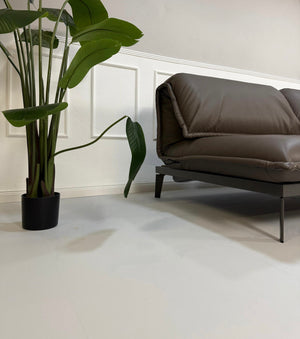 Gebrauchtes braunes Rolf Benz Designer Leder Sofa vor einer Wand, stilvoll und modern eingerichtet.