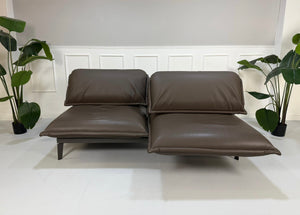 Gebrauchtes braunes Rolf Benz Designer Leder Sofa vor einer Wand, stilvoll und modern eingerichtet.