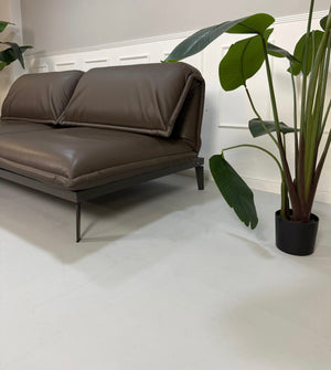Gebrauchtes braunes Rolf Benz Designer Leder Sofa vor einer Wand, stilvoll und modern eingerichtet.