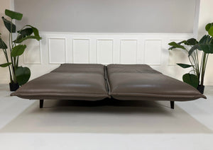 Gebrauchtes braunes Rolf Benz Designer Leder Sofa vor einer Wand, stilvoll und modern eingerichtet.