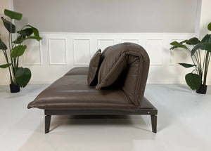 Gebrauchtes braunes Rolf Benz Designer Leder Sofa vor einer Wand, stilvoll und modern eingerichtet.