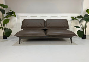 Gebrauchtes braunes Rolf Benz Designer Leder Sofa vor einer Wand, stilvoll und modern eingerichtet.