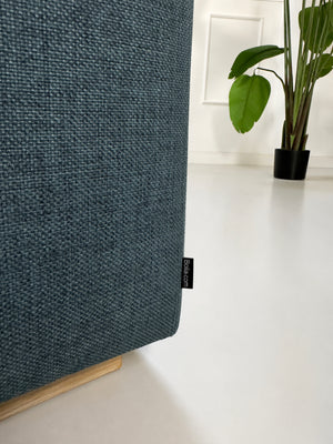 Gebrauchtes blaues Bolia Sepia Designer Stoff Sofa vor einer Wand, stilvoll und modern eingerichtet.