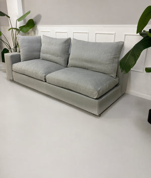 Gebrauchtes graues Flexform Groundpiece Designer Stoff Sofa vor einer Wand, stilvoll und modern eingerichtet.