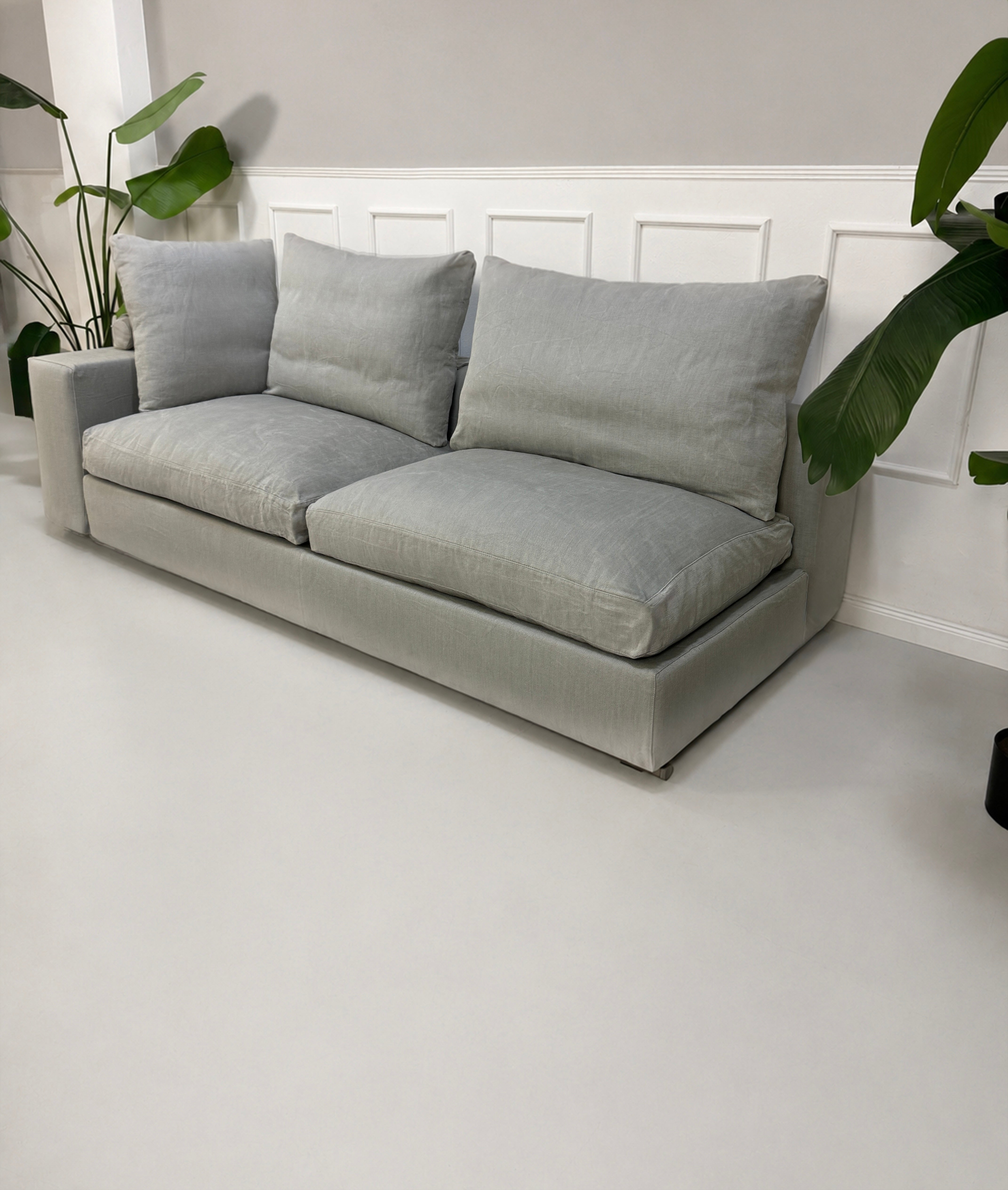 Gebrauchtes graues Flexform Groundpiece Designer Stoff Sofa vor einer Wand, stilvoll und modern eingerichtet.