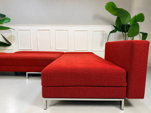 Gebrauchtes rotes Brühl FourTwo Designer Stoff Ecksofa vor einer Wand, stilvoll und modern eingerichtet.