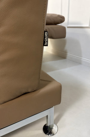 Gebrauchtes braunes Brühl Moule Medium Designer Leder Sofa vor einer Wand, stilvoll und modern eingerichtet.
