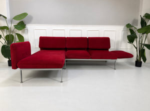 Gebrauchtes rotes Brühl Roro Medium Designer Stoff Ecksofa vor einer Wand, stilvoll und modern eingerichtet.