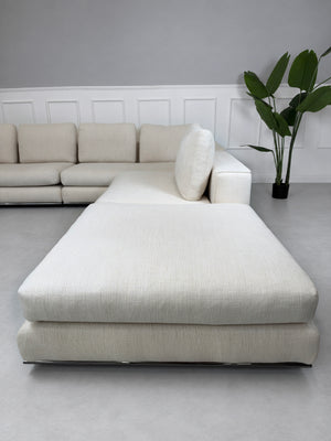 Gebrauchtes beiges Minotti Hamilton Designer Stoff Ecksofa vor einer Wand, stilvoll und modern eingerichtet.