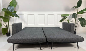Gebrauchtes graues Studio Copenhagen Copperfield Designer Stoff Sofa vor einer Wand, stilvoll und modern eingerichtet.