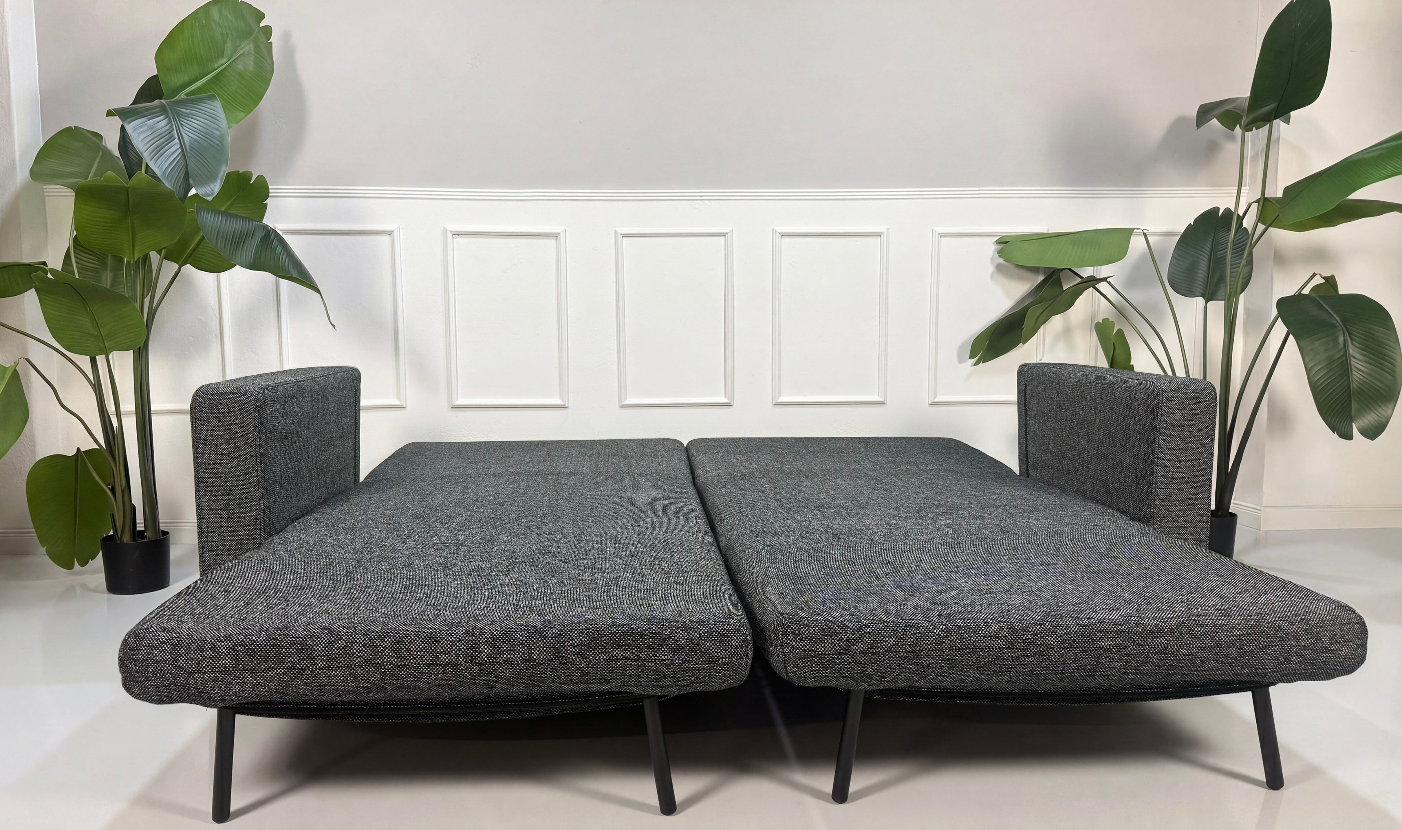 Gebrauchtes graues Studio Copenhagen Copperfield Designer Stoff Sofa vor einer Wand, stilvoll und modern eingerichtet.