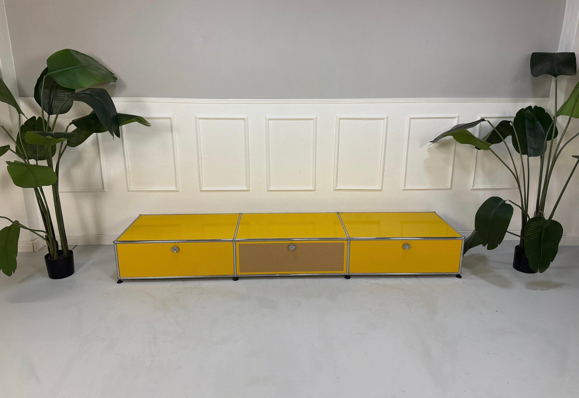 Gebrauchtes gelbes TV USM Haller Lowboard vor einer Wand, stilvoll und modern eingerichtet.