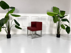 Gebrauchter roter Brühl Belami Designer Leder Sessel vor einer Wand, stilvoll und modern eingerichtet.